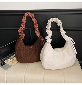 Detail of sherpa half-moon hobo bags in brown and beige with ruched PU leather handles