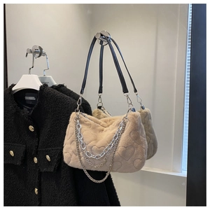Détail d'un sac à main en peluche beige avec motif cœur et triple chaîne en métal