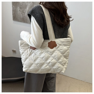 Detail of quilted tote bag featuring a leather flower charm and lightweight nylon texture