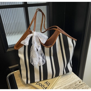 Detail of canvas tote with black and white stripes and a decorative white lace bow