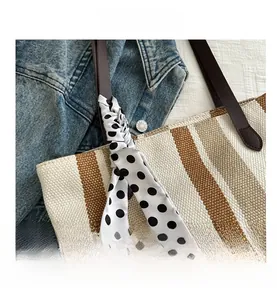 Close-up of striped woven tote bag featuring brown leather handles and polka dot silk scarf