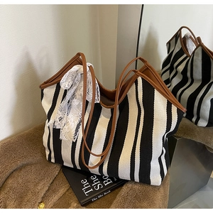 Detail of striped canvas tote with brown leather handles and a lace bow decoration