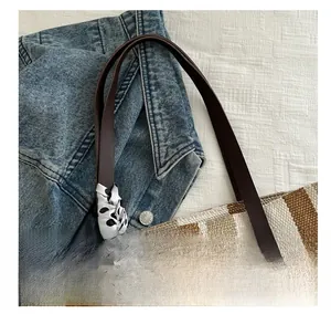 Close-up of canvas striped tote bag with brown leather handles and polka dot silk scarf