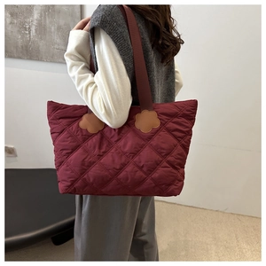 Detail of burgundy quilted tote bag with unique yellow petal-shaped leather strap accents