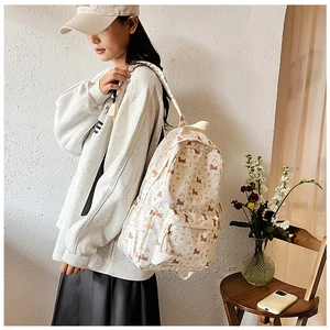 Détail du sac à dos en toile crème avec motifs de chiots porté par un mannequin