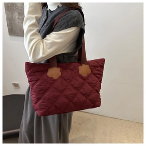 Macro shot of burgundy quilted tote bag showing rhombus stitching and petal leather detail