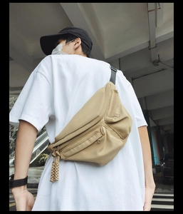 Detail of khaki functional chest bag with layered zippers and tactical woven straps