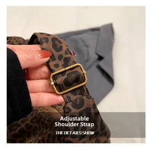 Close-up of leopard tote bag with adjustable fabric strap and vintage metal buckle