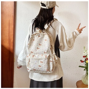Détail d'un sac à dos crème mignon avec imprimé chiots et poche latérale à cordon