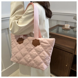 Detail of pink quilted tote bag with floral accents and stitched diamond pattern