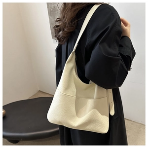 Close-up of cream white tote bag with soft leather texture and dual front pockets