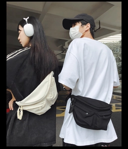 Rear view of models wearing large utility crossbody bags in beige and black nylon fabric