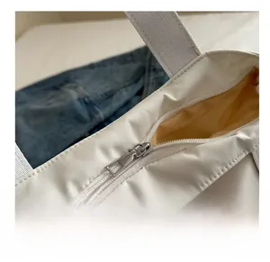 Detailed close-up of the smooth silver zipper closure on a white minimalist tote bag