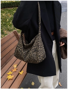 Detail of leopard print canvas tote bag with wide shoulder strap in outdoor autumn setting