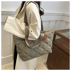 Detail of khaki grey quilted tote bag featuring diamond patterns and floral patches
