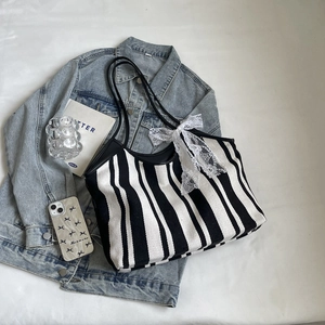 Retro black and white striped canvas tote bag with lace bow on blue denim jacket
