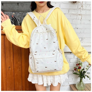 Détail d'un sac à dos blanc style japonais avec motif floral et chien porté par un modèle