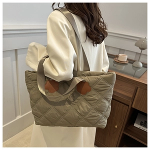 Close-up of olive green quilted tote bag with brown leather floral accents and durable texture