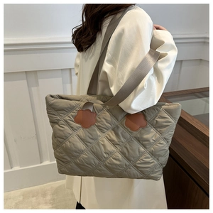 Close-up of khaki quilted tote bag with brown floral leather patches and wide strap