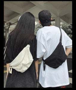 Outdoor street view of black and white cross-body bags worn by male and female models