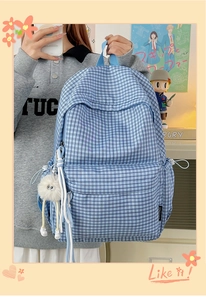 Detail eines blauen karierten Schulrucksacks mit Kordelzug-Seitentasche und Plüsch-Anhänger