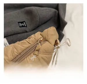Detailed close-up of premium gold zipper and embroidered bow on khaki quilted tote bag