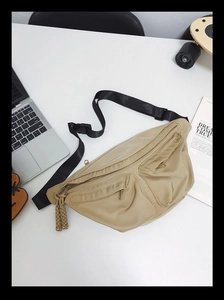 Top view of khaki nylon crossbody bag with multiple zip pockets on a stylish desktop