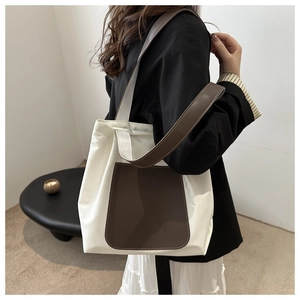 Detail of the white nylon tote bag with a brown leather pocket shown on a female model