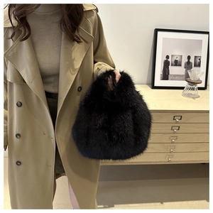 Detail view of the soft black faux fur texture on a stylish plush handbag