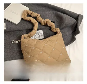 Detailed close-up of khaki quilted hobo bag with white bow embroidery and scrunchie strap