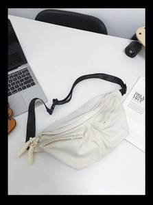 Detail view of a beige nylon crossbody bag with multiple zippers and woven cord accents