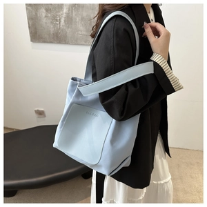 Detail shot of light blue nylon tote bag with leather pocket and shoulder strap on model