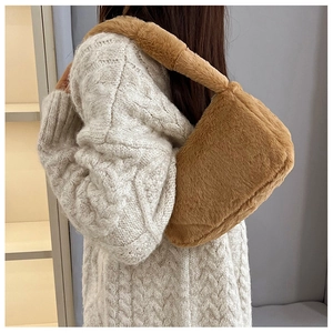 Close-up of fluffy brown plush shoulder bag paired with white cable knit sweater