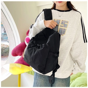 Detail of black nylon backpack with drawstring and adjustable buckles on a model