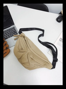 Detail view of a beige nylon crossbody bag with multi-pocket design and adjustable strap