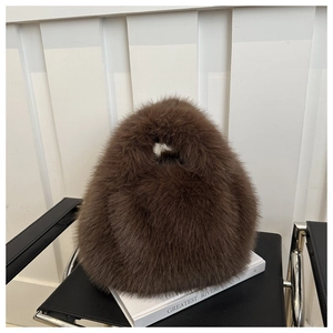 Detail of plush faux fur handbag in dark brown resting on a white decorative book