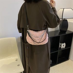 Sac à main rose en peluche avec motif cœur et chaînes argentées sur un manteau foncé