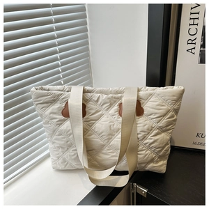 Detailed view of cream quilted tote bag featuring brown bear ear leather patch detail