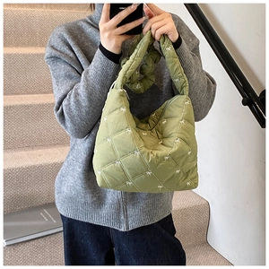 Detailed embroidery of white bows on green quilted fabric with ruffled shoulder strap