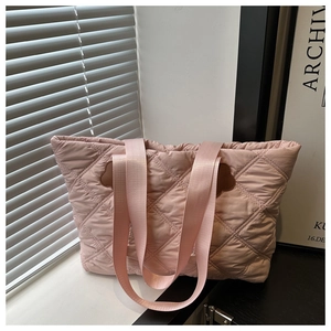 Close-up of pink quilted tote bag with floral leather patch and wide shoulder strap