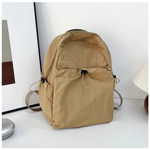 Macro shot of khaki nylon backpack featuring drawstring front pocket and storage side pockets