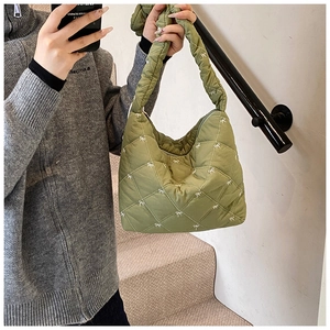 Close-up of light green quilted shoulder bag with white bow embroidery detail
