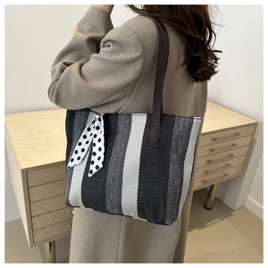 Detail view of large striped tote bag with leather straps and polka dot ribbon detail
