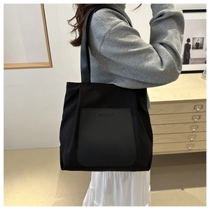 Detail shot of black tote bag with premium texture and embossed logo by a vintage cabinet