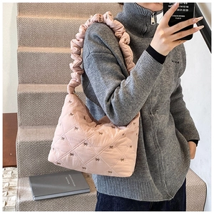 Detail of pink quilted shoulder bag with bow embroidery and ruched cloud strap