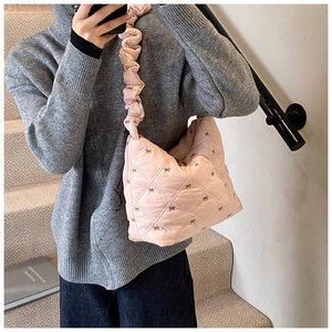 Detailed view of pink quilted tote bag with bow embroidery and ruched strap texture