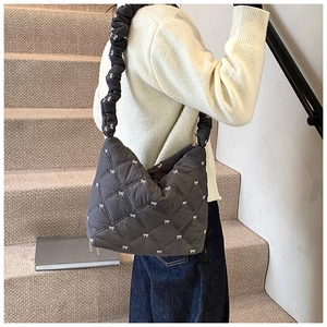 Detail of dark grey quilted shoulder bag with bow embroidery and ruffled strap