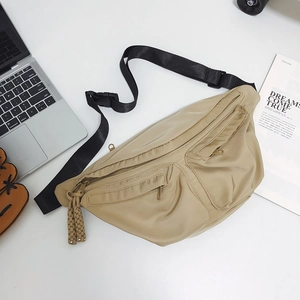 Close-up of khaki nylon chest bag with triple zipper pockets and woven pullers