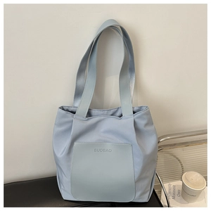 Detail showing the light blue waterproof tote bag with a leather front pocket and long straps