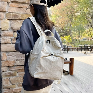 Large beige nylon backpack with drawstrings for students in a casual outdoor setting